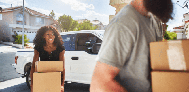 relocating to atlanta couple carrying boxes into new home