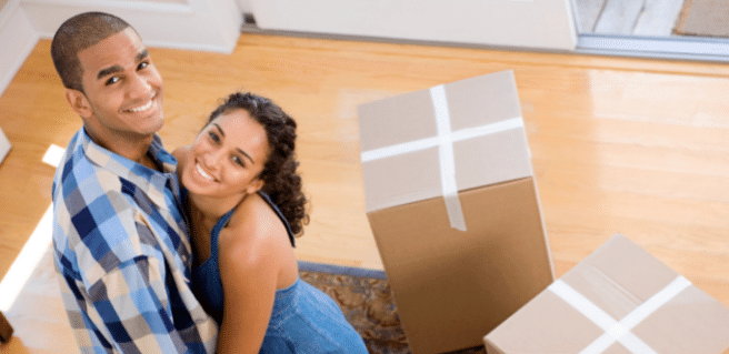 Happy Couple sitting in new home surrounded by boxes to demonstrate mortgage don'ts