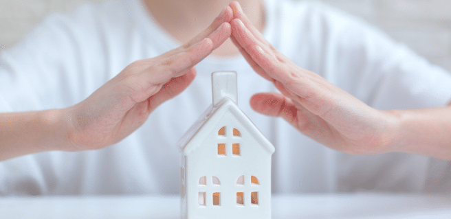 Photo of two hands covering a home to depict home warranties and their importance.