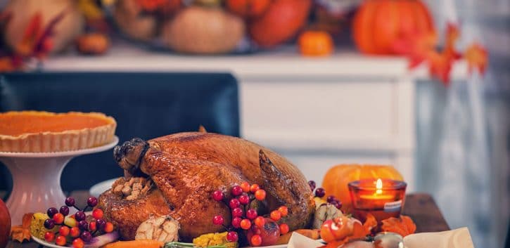 Table is set up for celebrating Thanksgiving. On the table is a traditional roasted turkey with side dishes and autumn decoration. Atlanta restaurants open on Thanksgiving