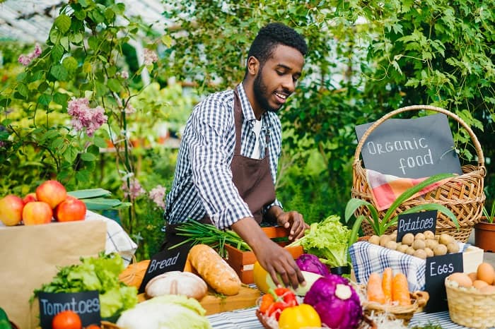 farmers market with man attending table of vegetables