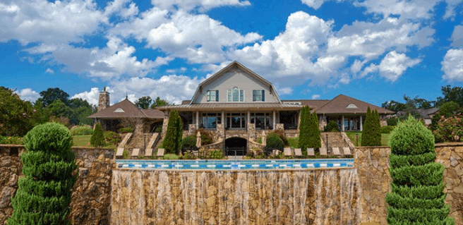 view of Sterling on the Lake community clubhouse exterior with view of pool edge and waterfall