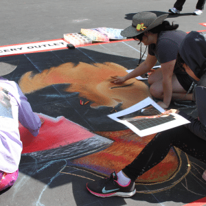 Photo of people working on a street mural to advertise the ELEVATE Art Festival