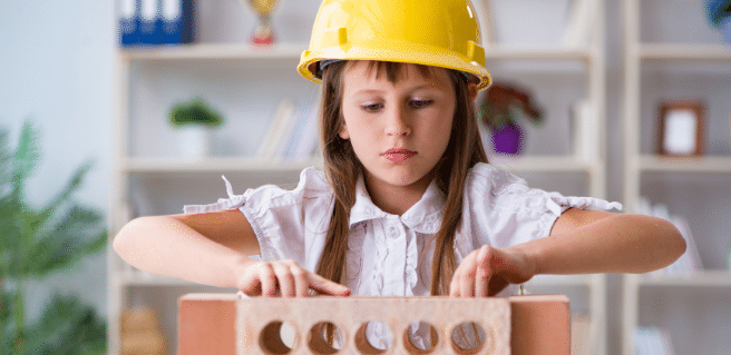 construction workforce education image of young girl in a hard hat with a brick