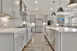 bright white kitchen with pendant lights and light wood floor.