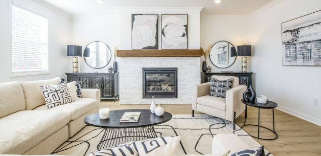 Traton Homes Avenbrook decorated model living room with stacked stone white fireplace and wooden floors