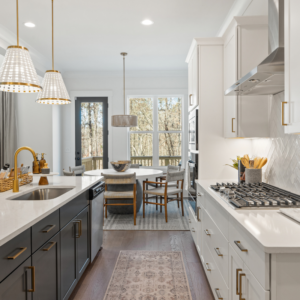 Arden on Lanier model home kitchen with walnut and white cabinetry, quartz countertops, pendant lighting with gold hardware
